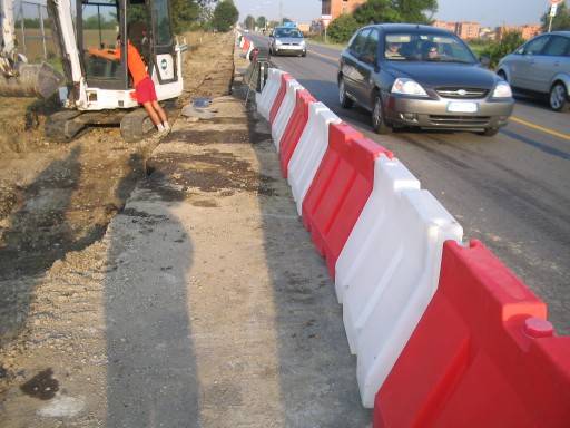 Si prepara la scavatrice, sulla strada passano le auto